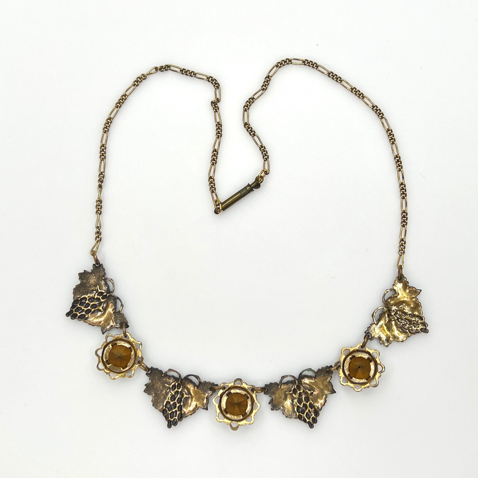 Back view of vintage enamel grape necklace with alternating rhinestone and leaf panels.
