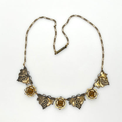 Back view of vintage enamel grape necklace with alternating rhinestone and leaf panels.