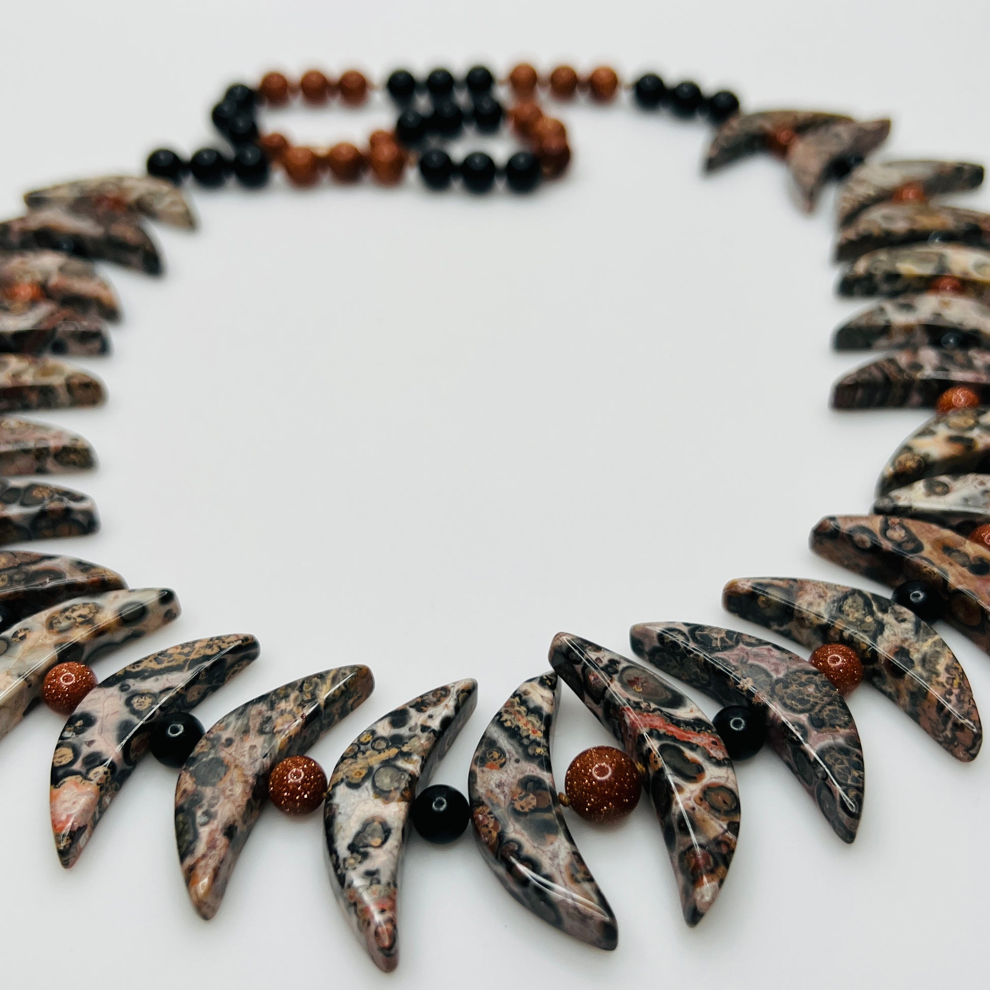Close-up of asteroid jasper necklace with goldstone and obsidian beads