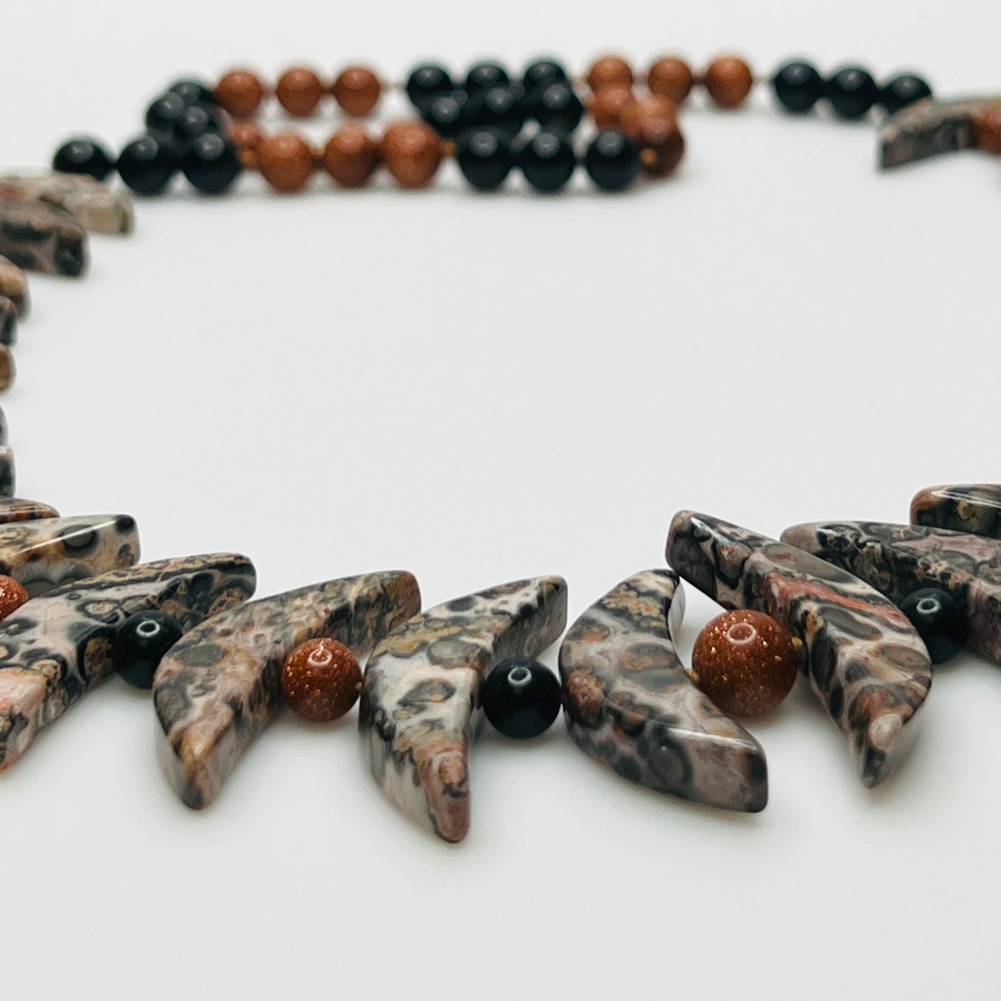 Close-up of asteroid jasper necklace with goldstone and obsidian beads
