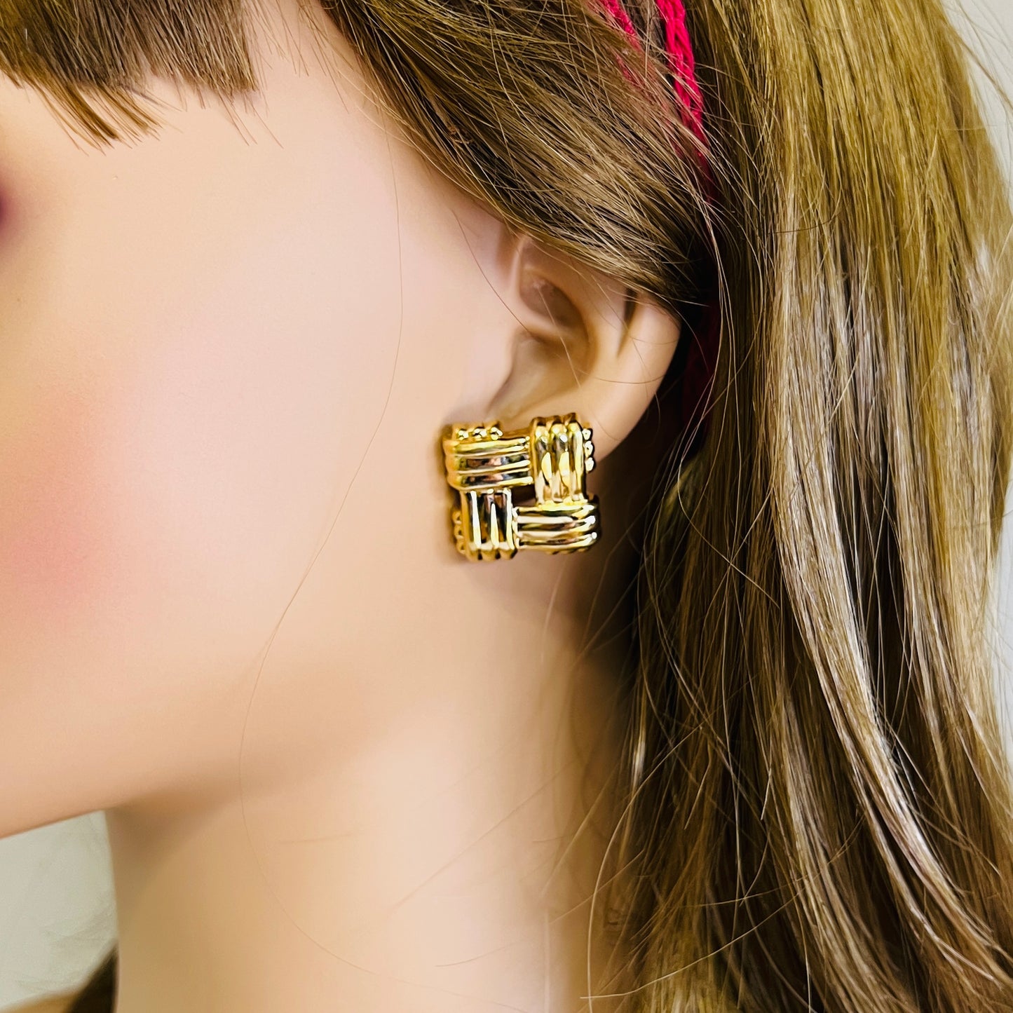 Gold tone geometric Avon earrings worn on mannequin ear
