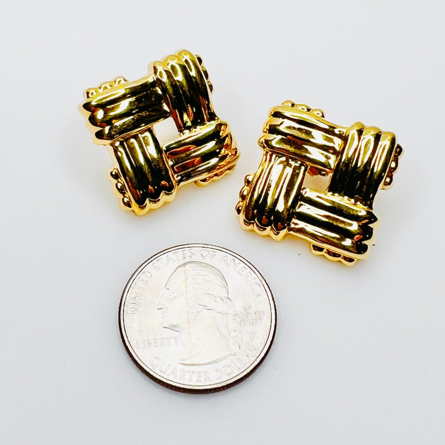 Vintage Avon pierced stud earrings beside quarter for size comparison