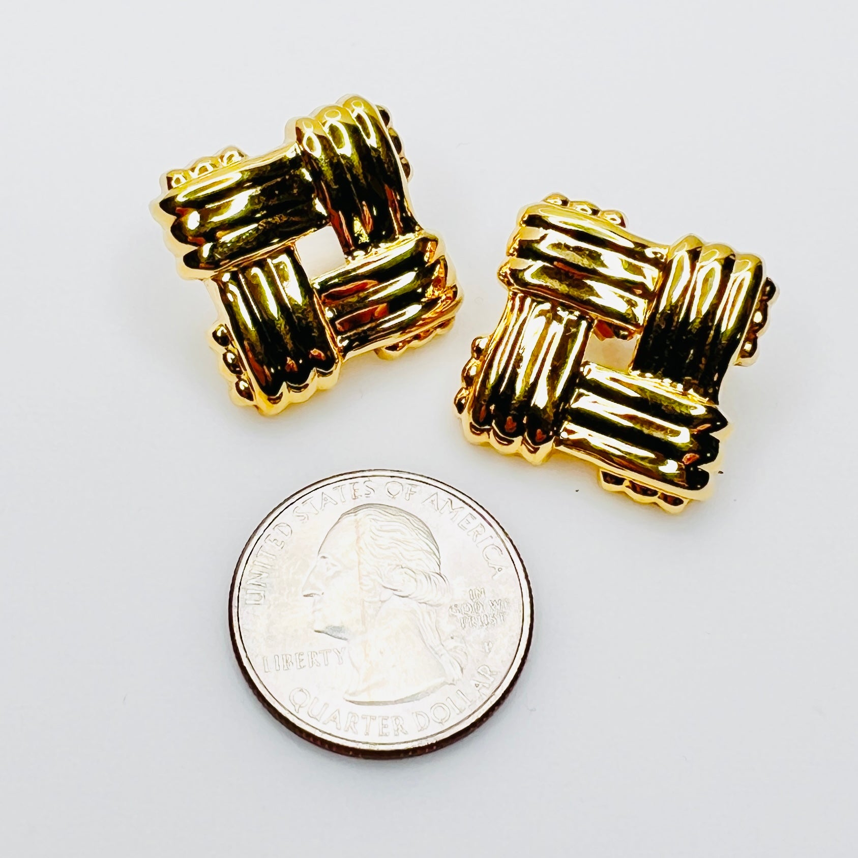 Vintage Avon pierced stud earrings beside quarter for size comparison
