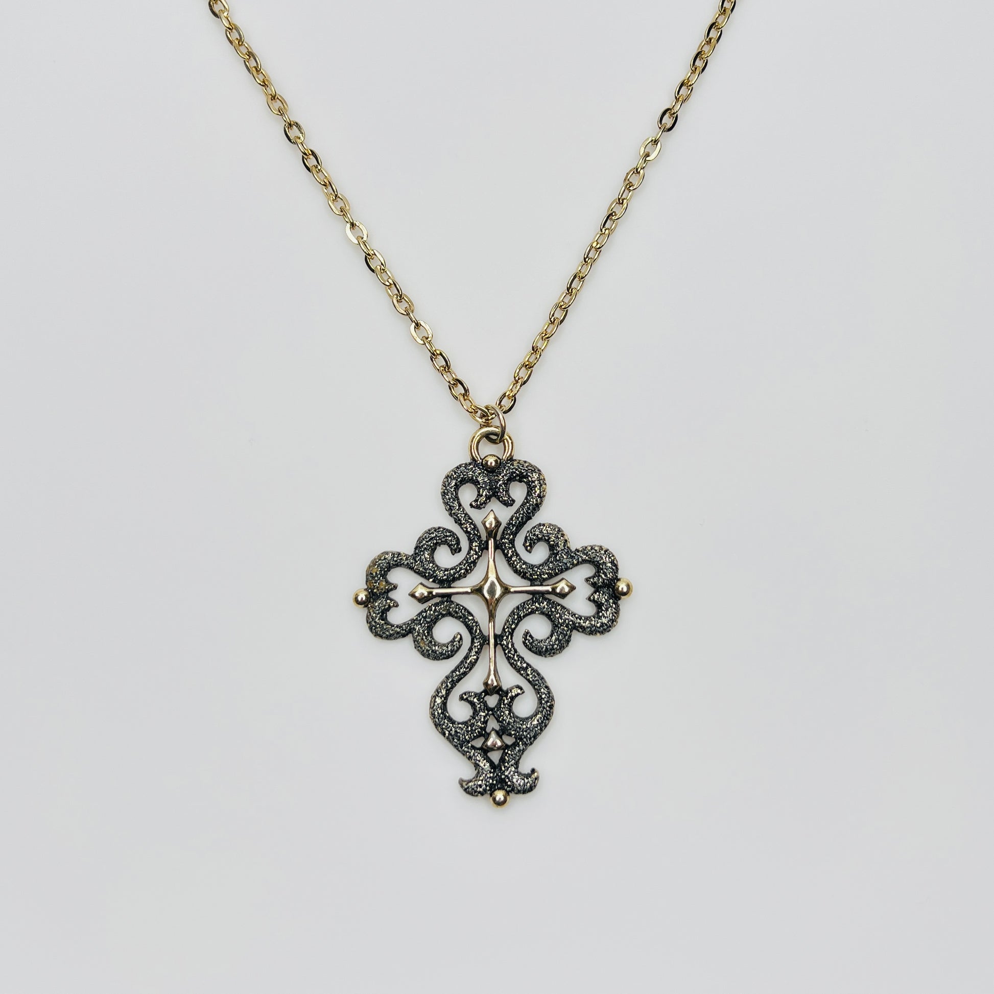 Large gold tone cross pendant necklace with textured filigree design