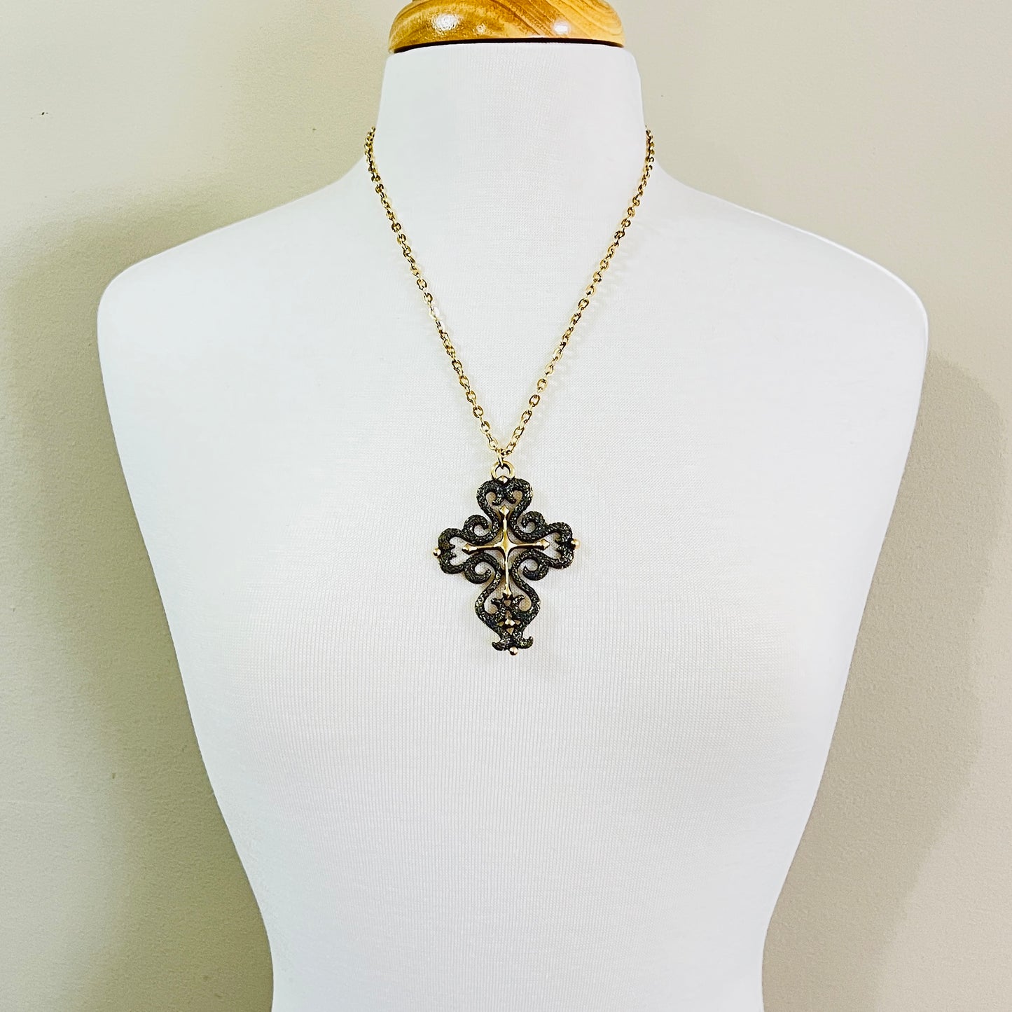 Vintage cross necklace displayed on mannequin with long chain
