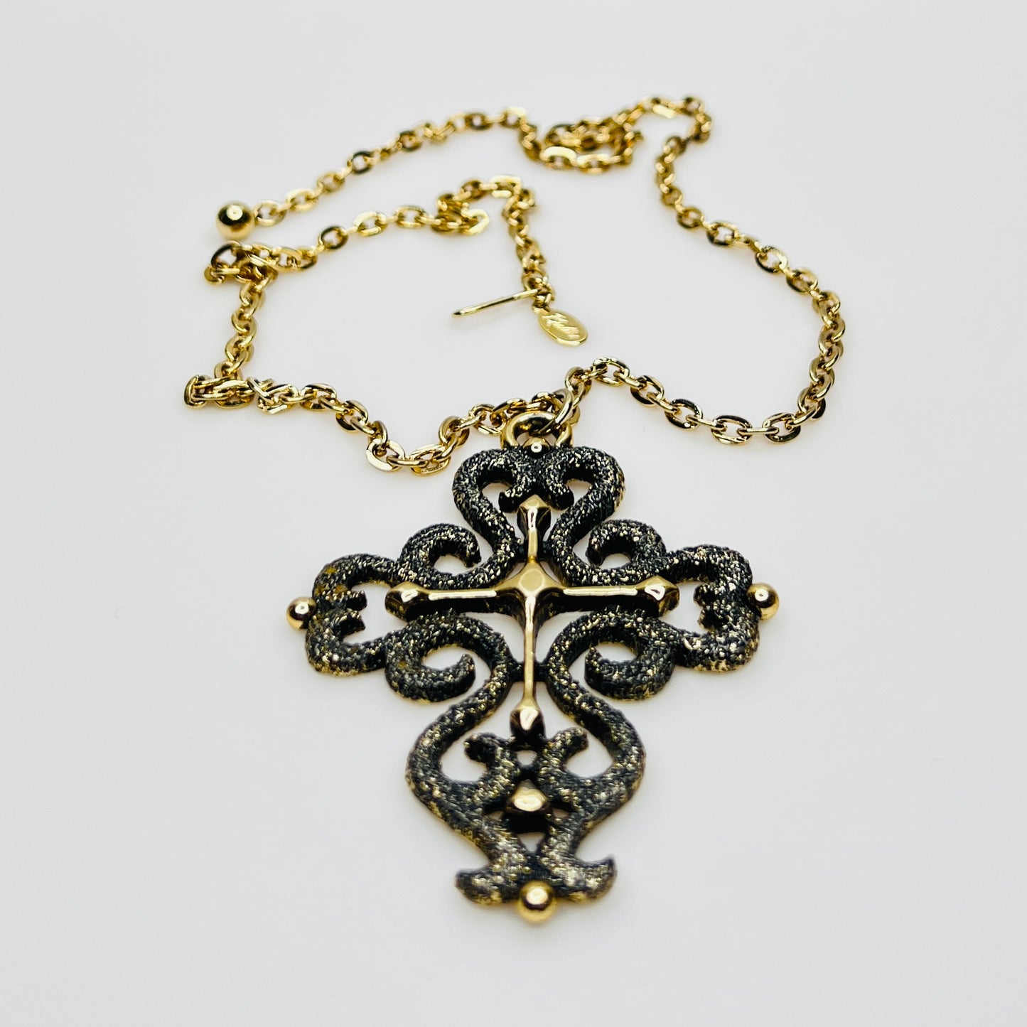 Close-up of ornate cross pendant with dimensional texture