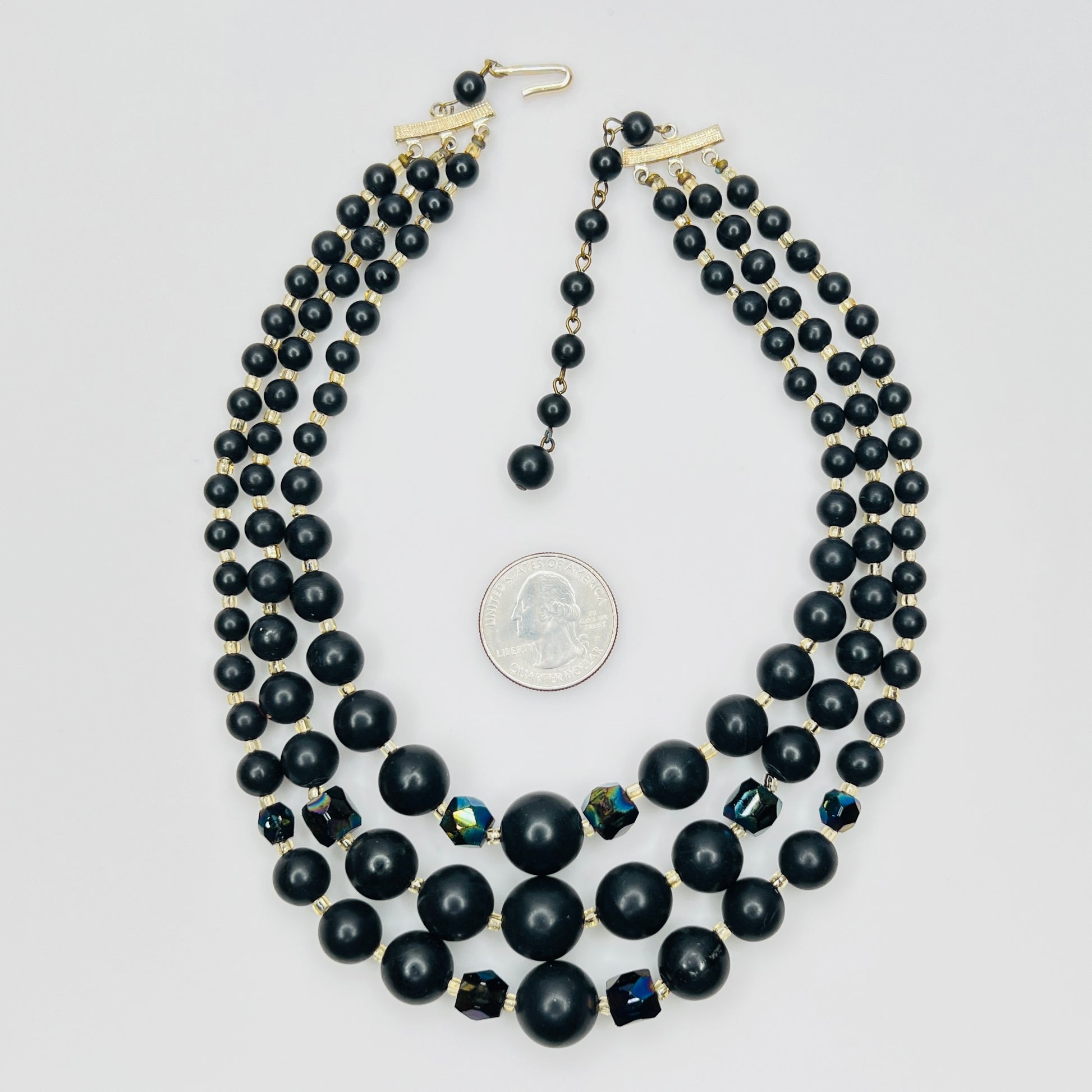 Vintage Japanese black bead necklace beside quarter for scale