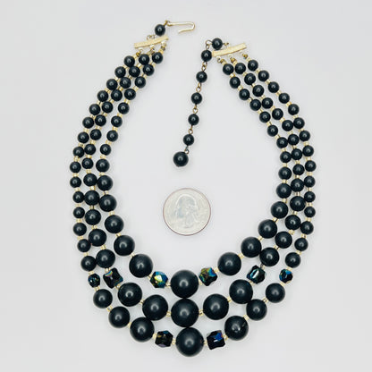 Vintage Japanese black bead necklace beside quarter for scale