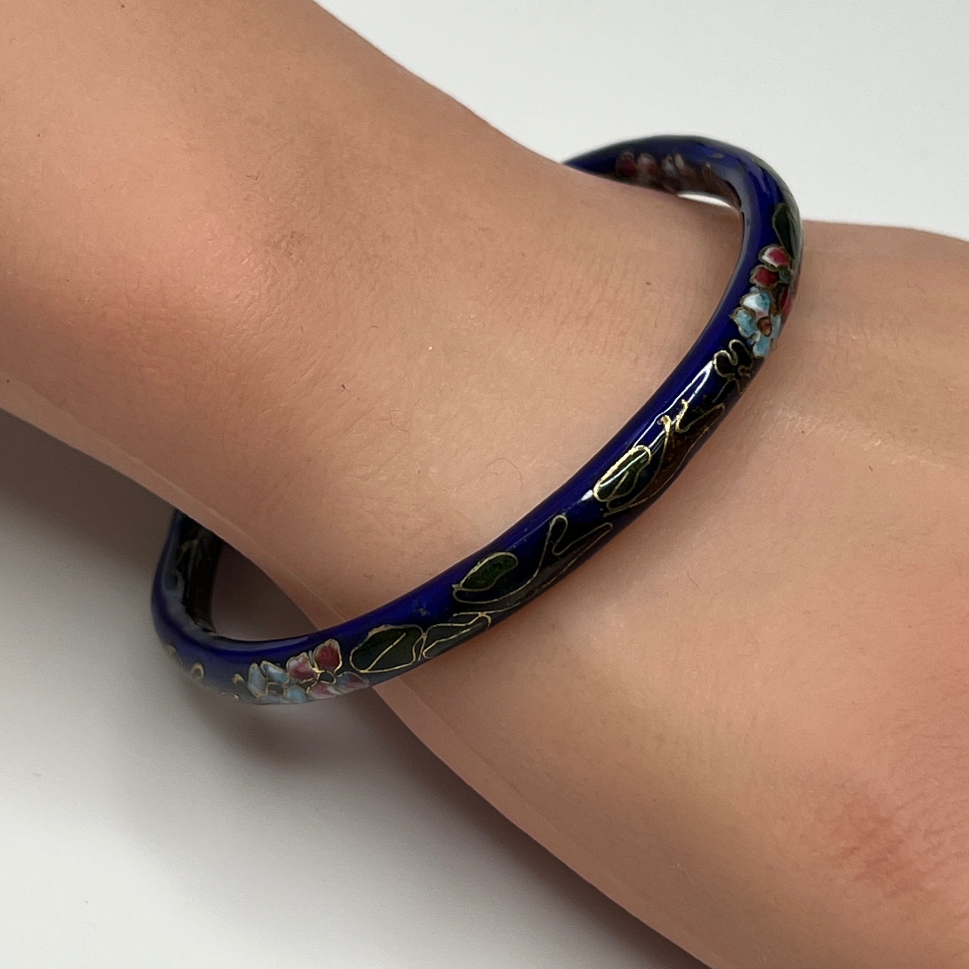 Dark blue cloisonné bangle bracelet with floral design on wrist