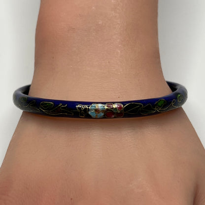 Dark blue cloisonné bangle bracelet with floral design on wrist