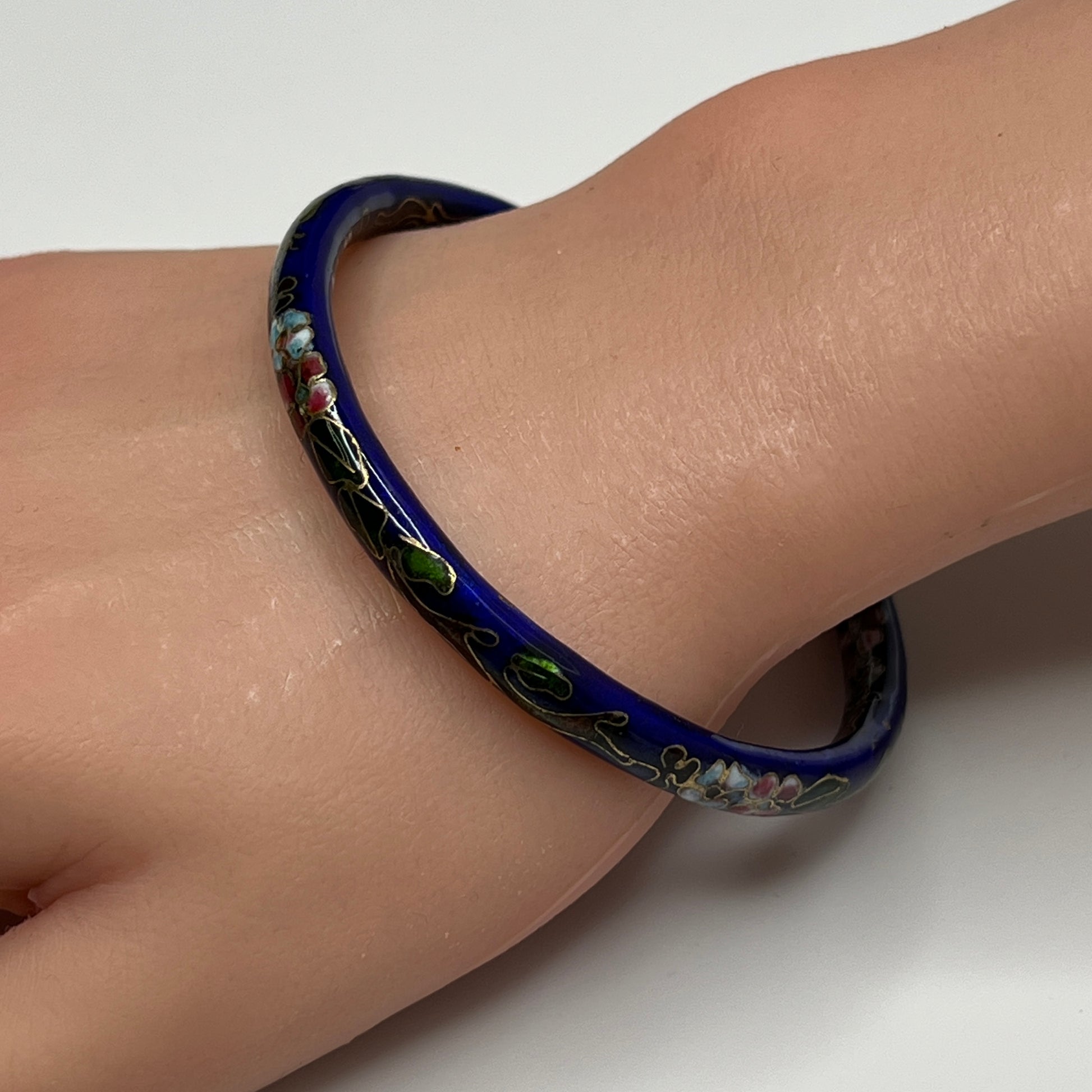Dark blue cloisonné bangle bracelet with floral design on wrist
