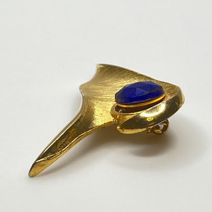 Modernist gold-tone brooch with sculptural wave shape and cobalt blue rhinestone center