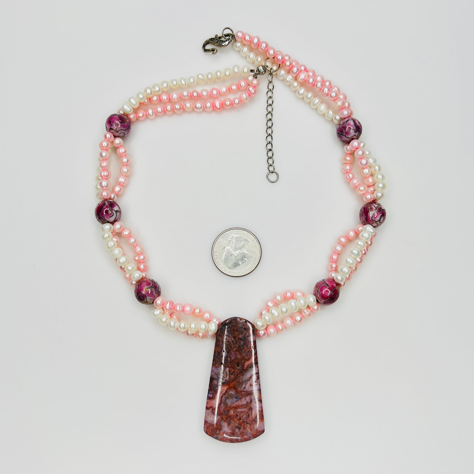 Close-up of polished Cotton Candy Agate pendant suspended from pink and white pearl strands