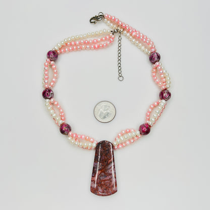 Close-up of polished Cotton Candy Agate pendant suspended from pink and white pearl strands