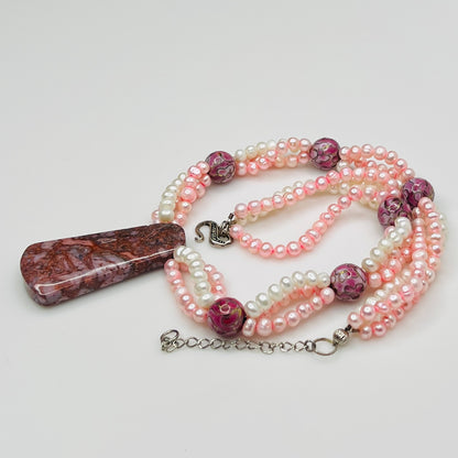 Close-up of polished Cotton Candy Agate pendant suspended from pink and white pearl strands