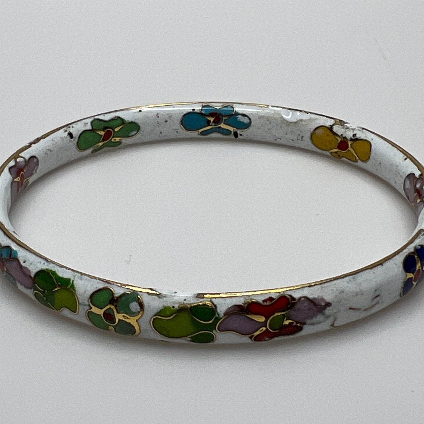 Close-up of enamel flower details on round white cloisonné bangle