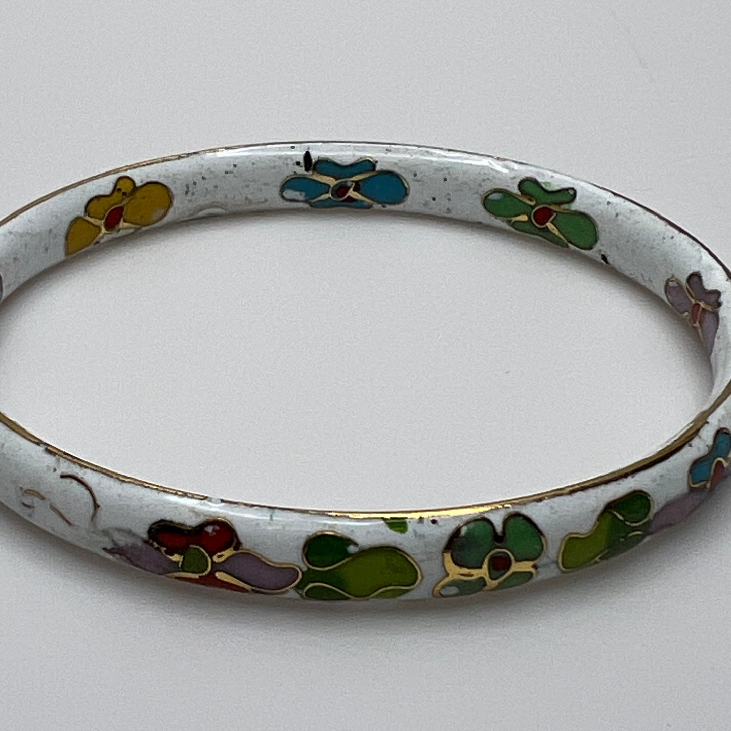Close-up of enamel flower details on round white cloisonné bangle