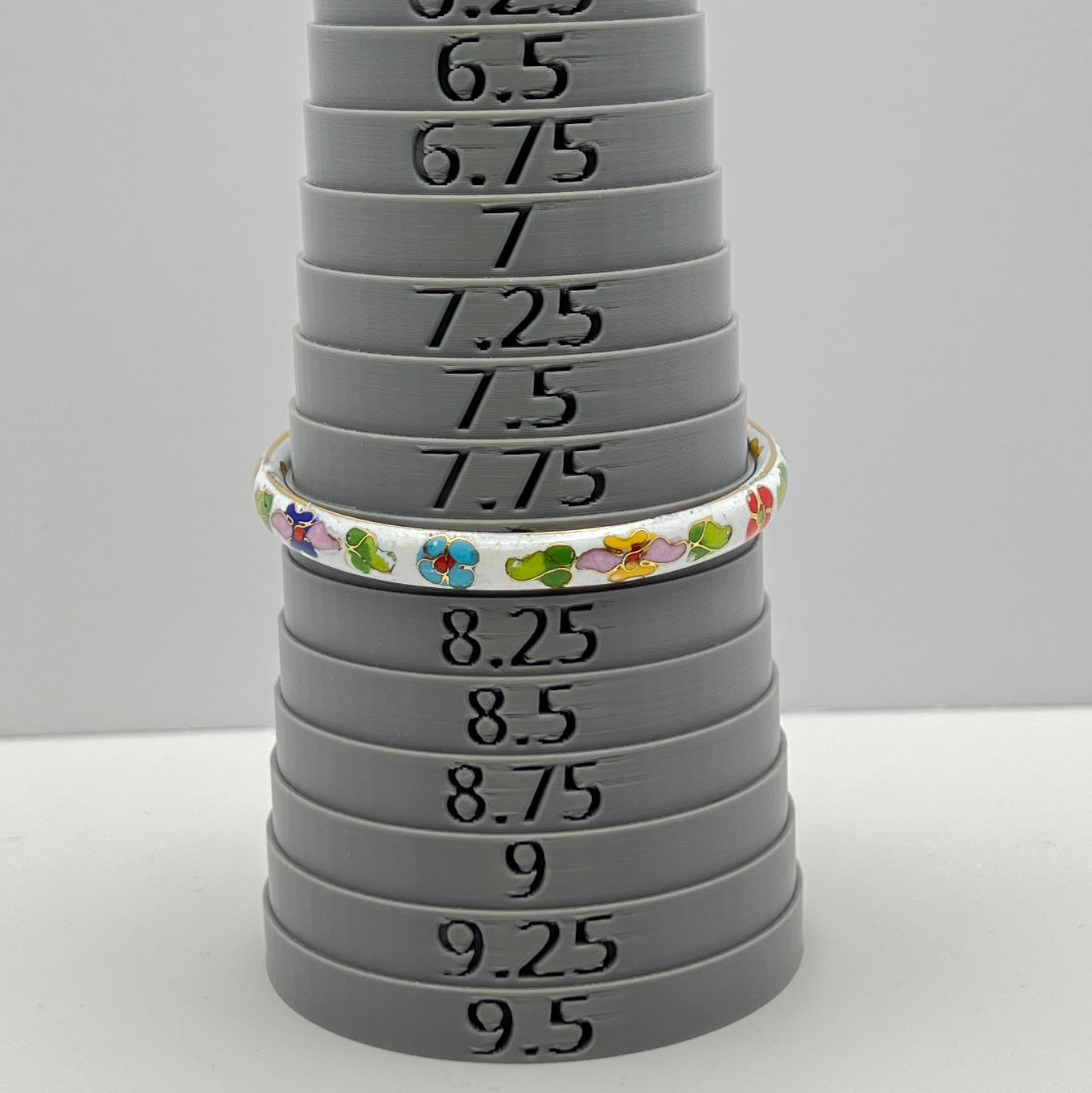 Close-up of enamel flower details on round white cloisonné bangle