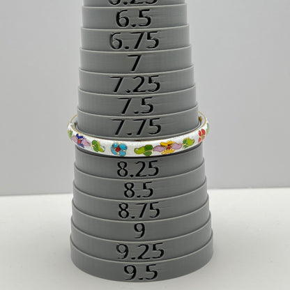 Close-up of enamel flower details on round white cloisonné bangle