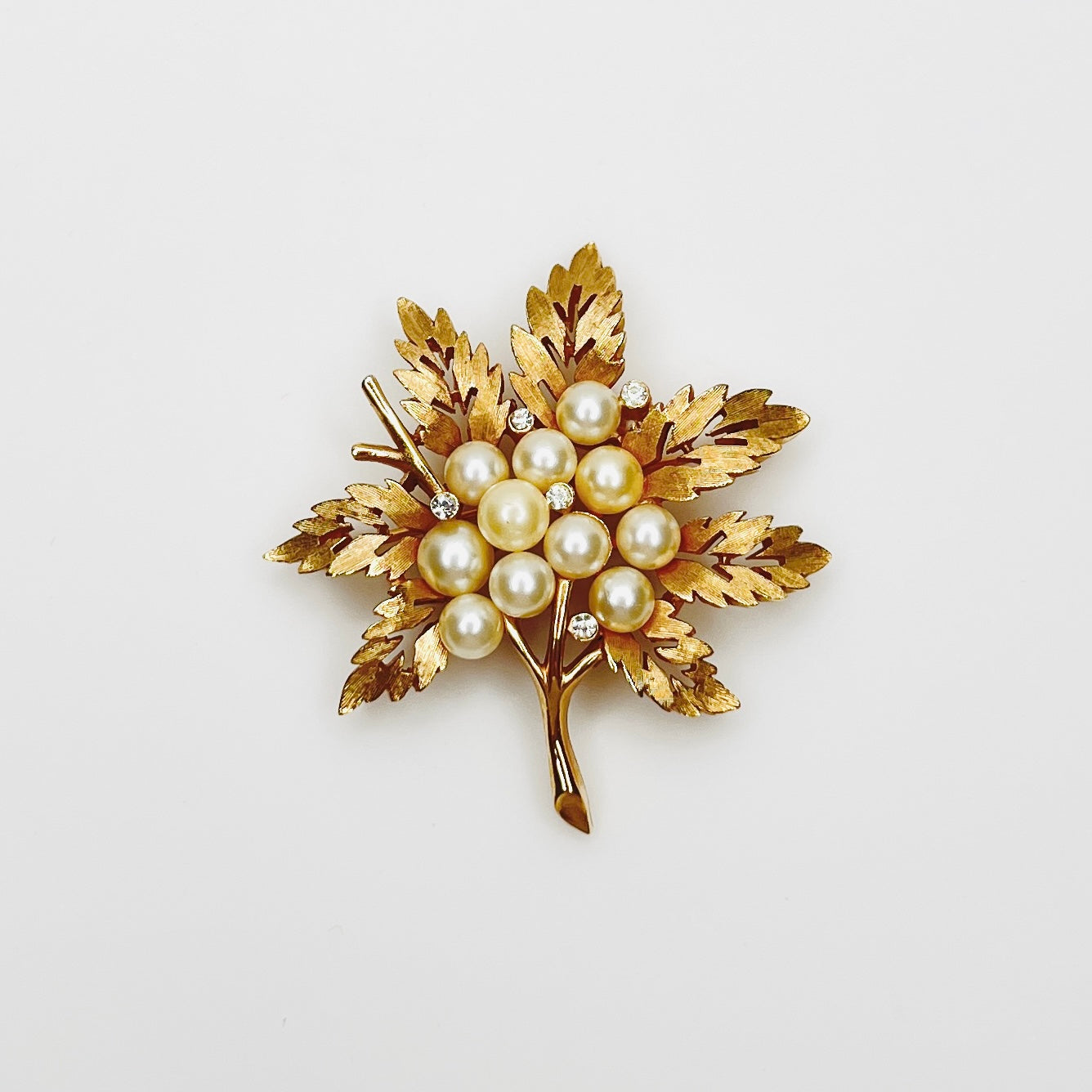 Vintage Crown Trifari gold tone leaf brooch with faux pearl cluster and rhinestones