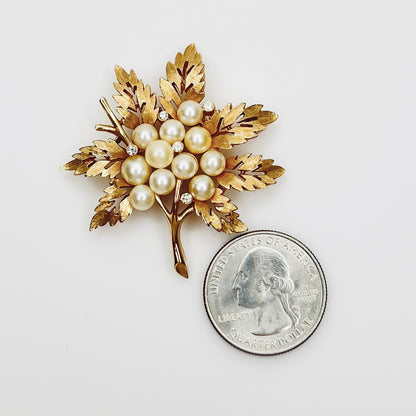 1950s Trifari pearl and rhinestone botanical brooch beside quarter for scale