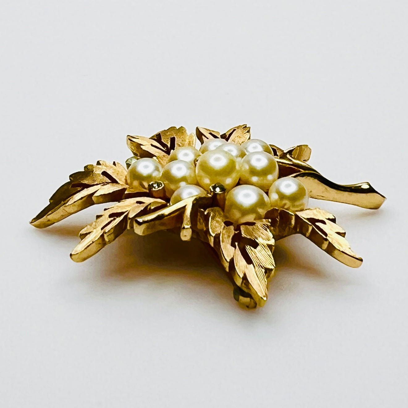 Side view of vintage Crown Trifari gold leaf brooch with faux pearls