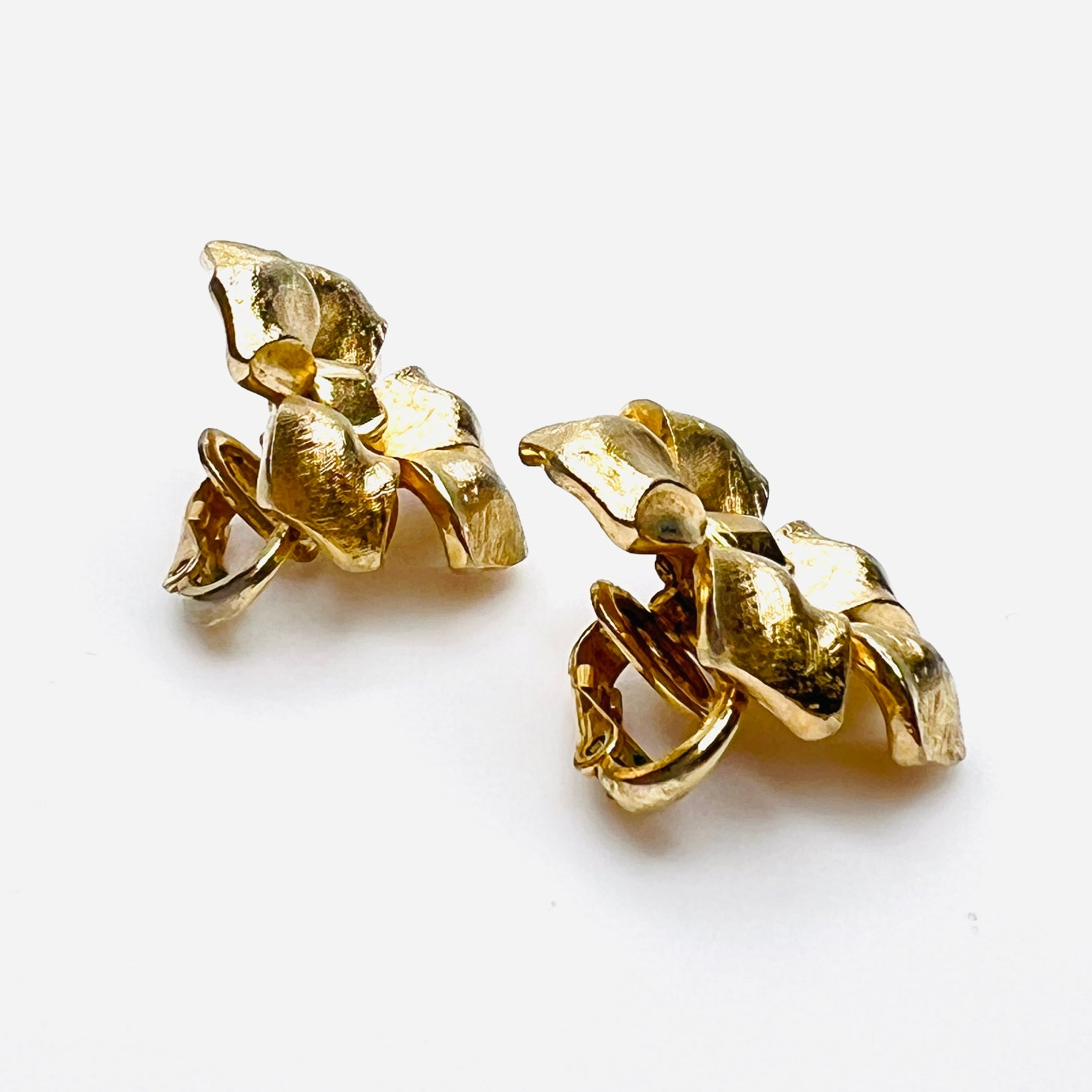 Side view of vintage Crown Trifari gold flower clip earrings.