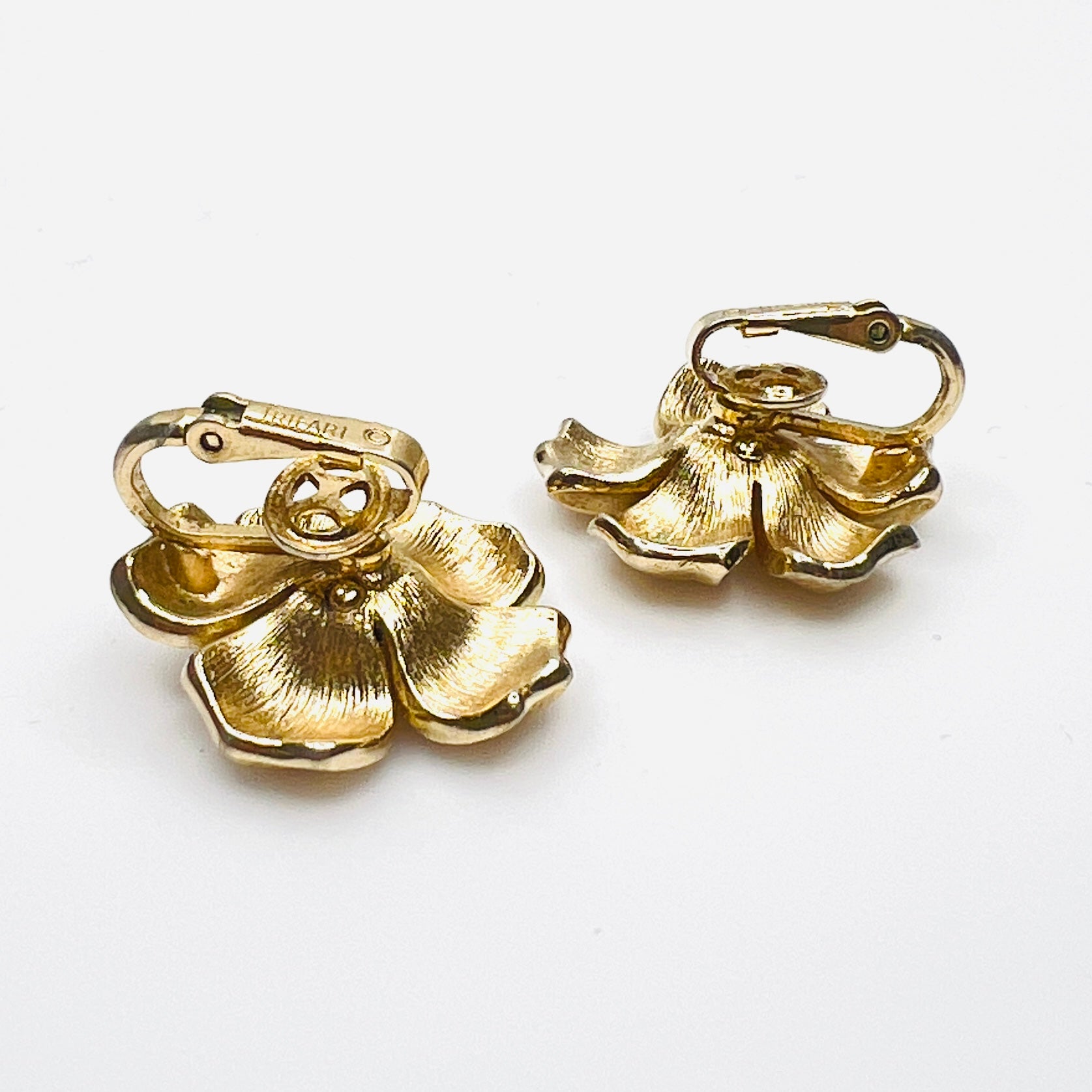 Side view of vintage Crown Trifari gold flower clip earrings.