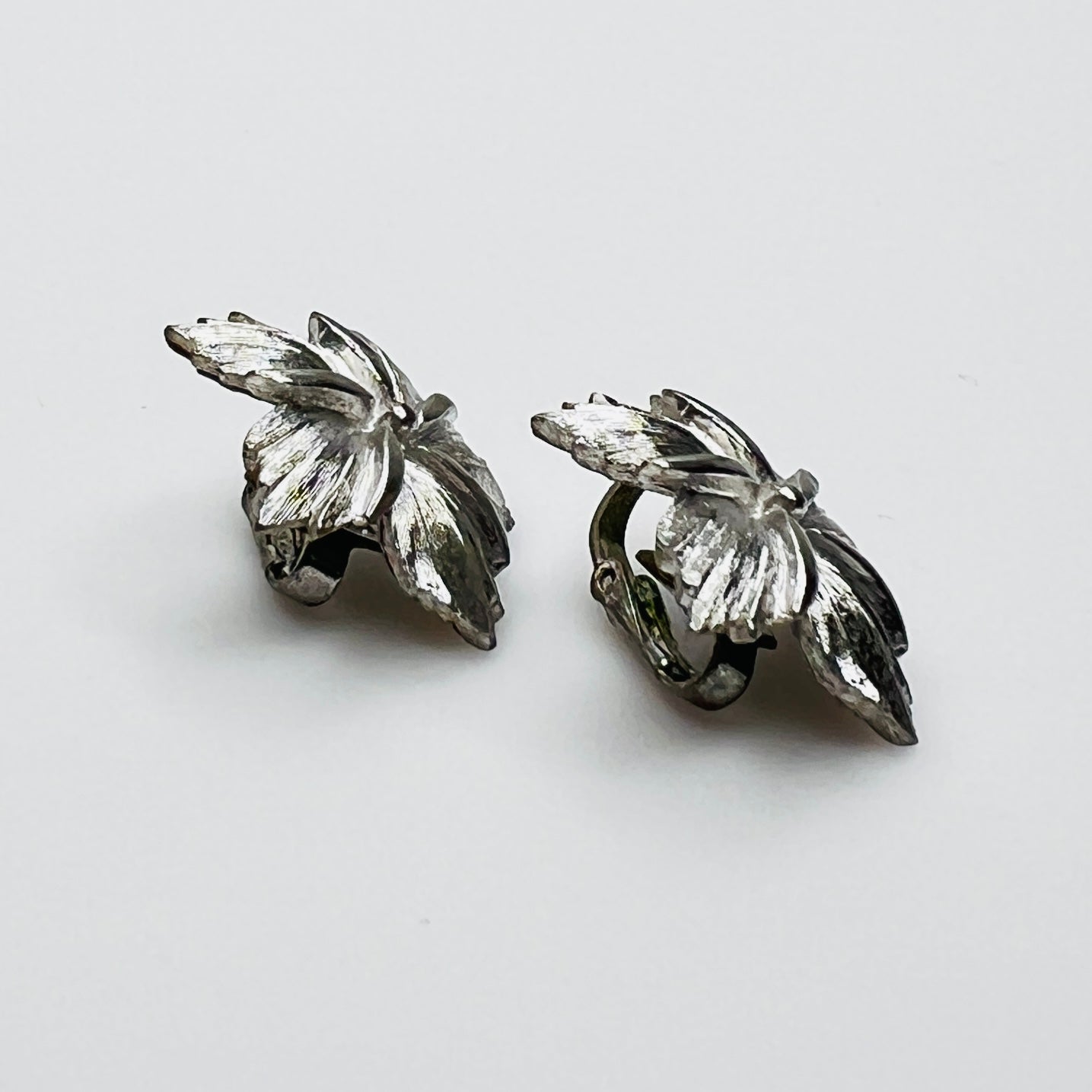 Side view of dimensional silver flower clip earrings