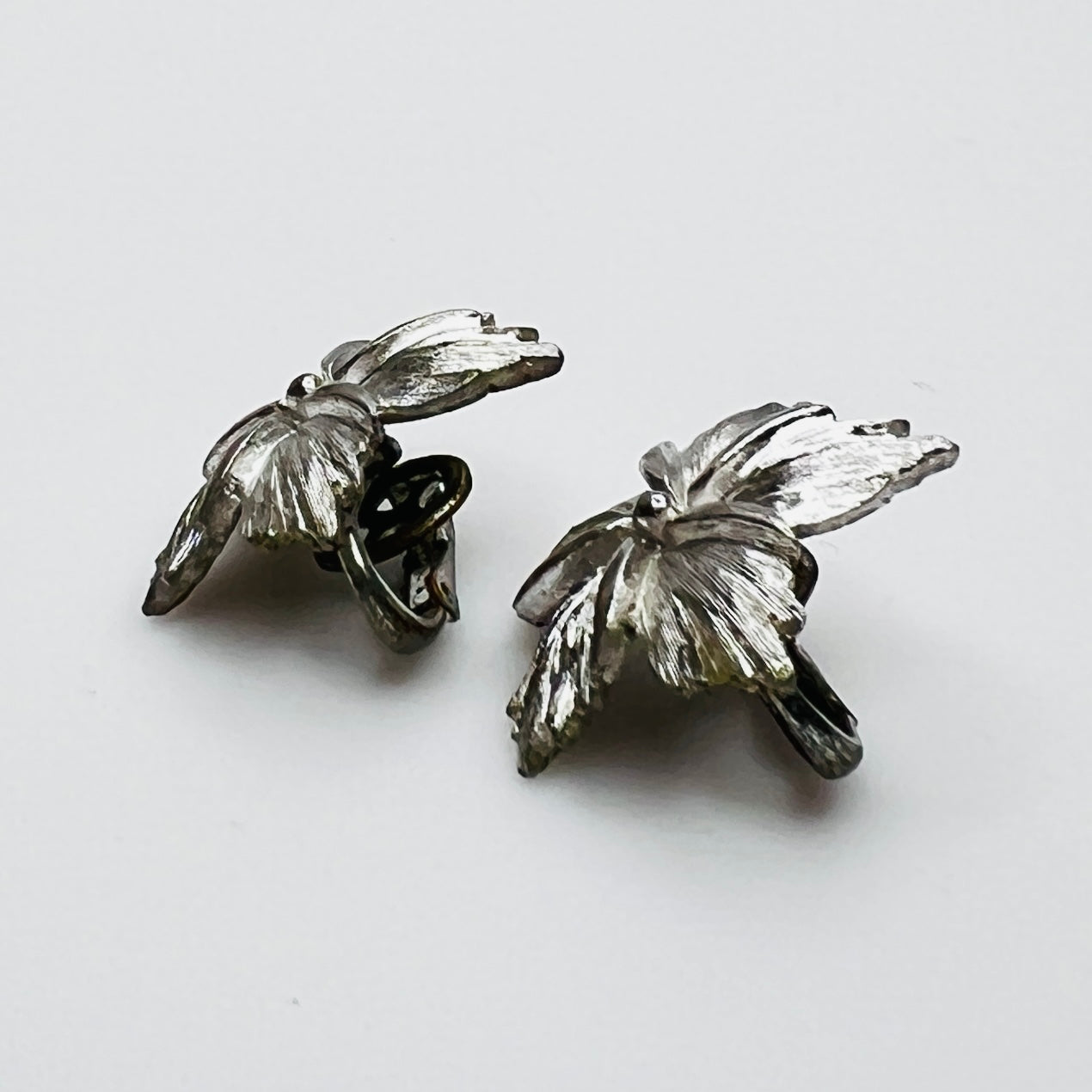 Side view of dimensional silver flower clip earrings