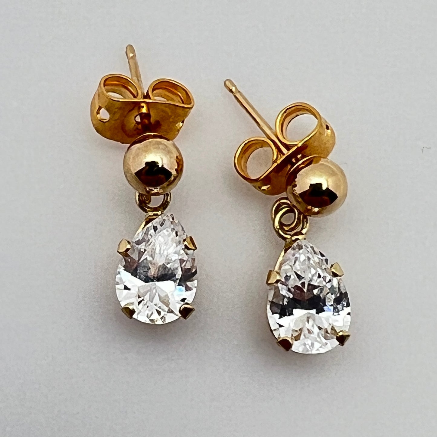 Close-up of vintage gold drop earrings with prong-set stones