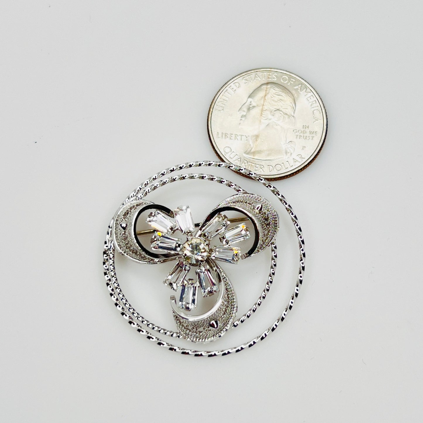 Ann Lee brooch with crystal center next to coin for scale