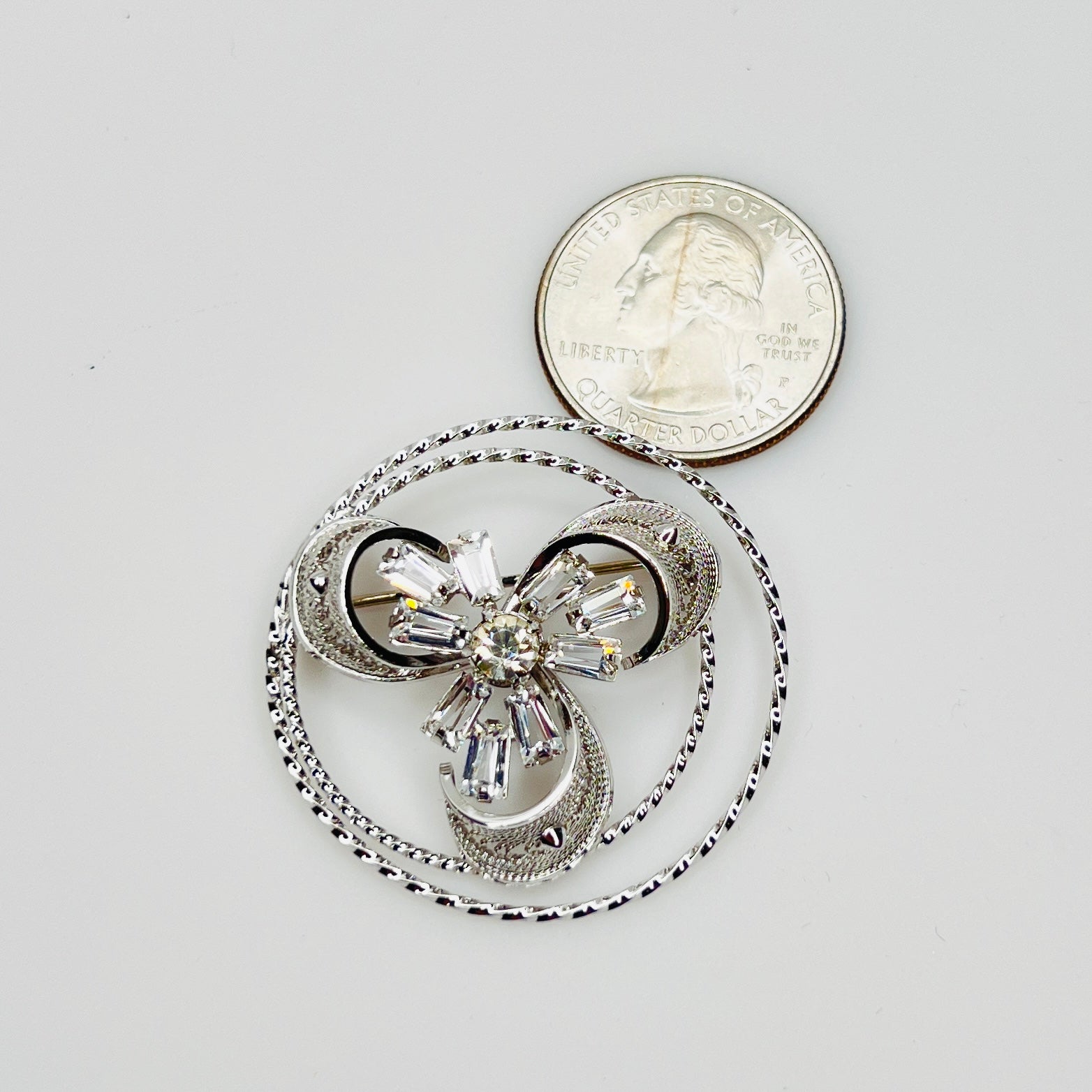 Ann Lee brooch with crystal center next to coin for scale