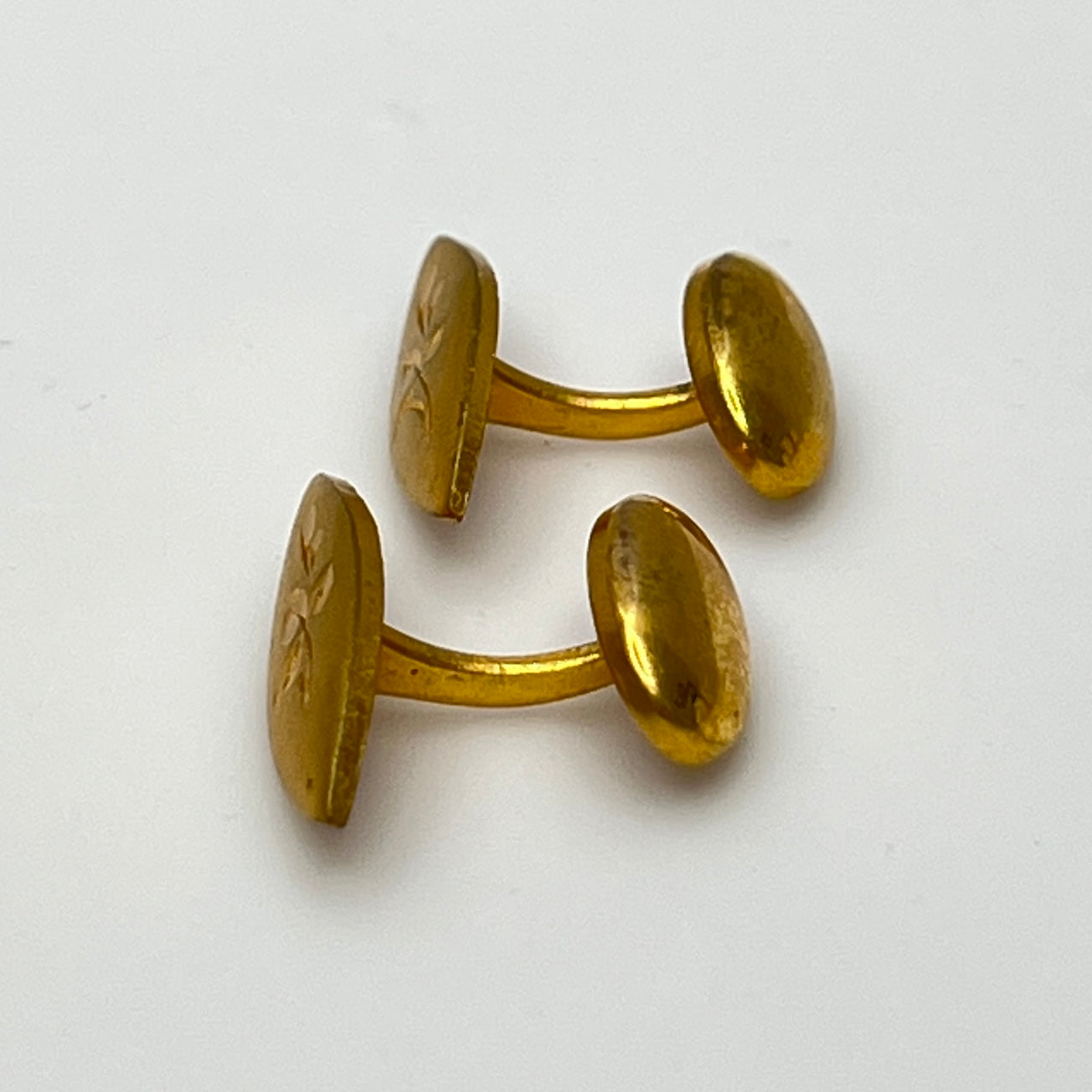 Side view of curved bar Edwardian-style gold cufflinks with floral engraving