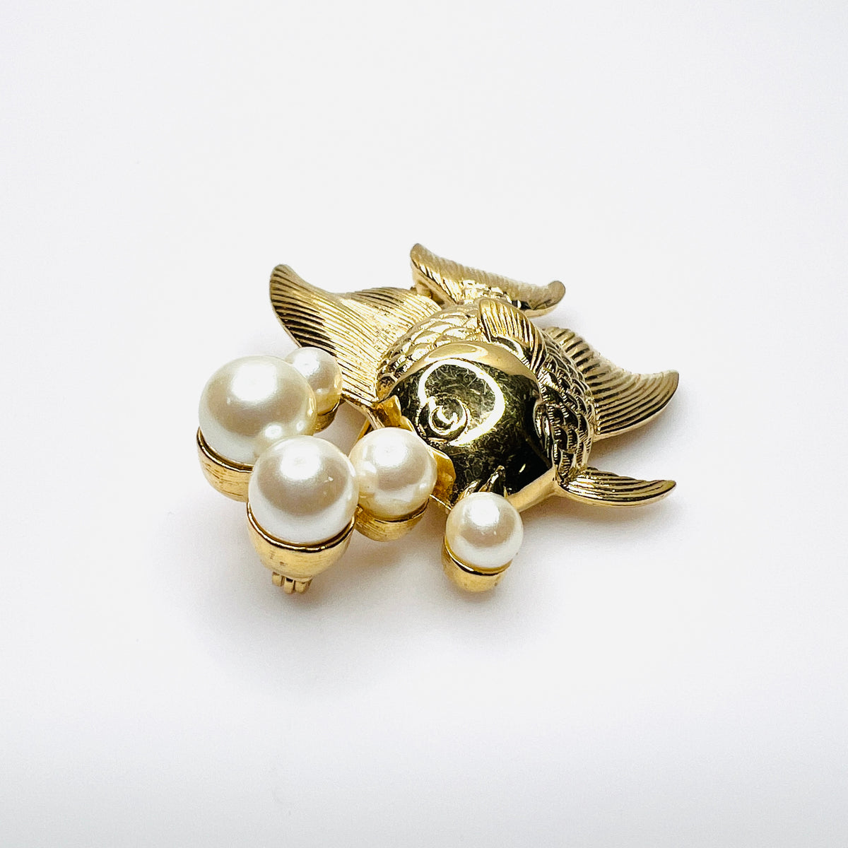 Side view of dimensional gold tone fish brooch with creamy faux pearls