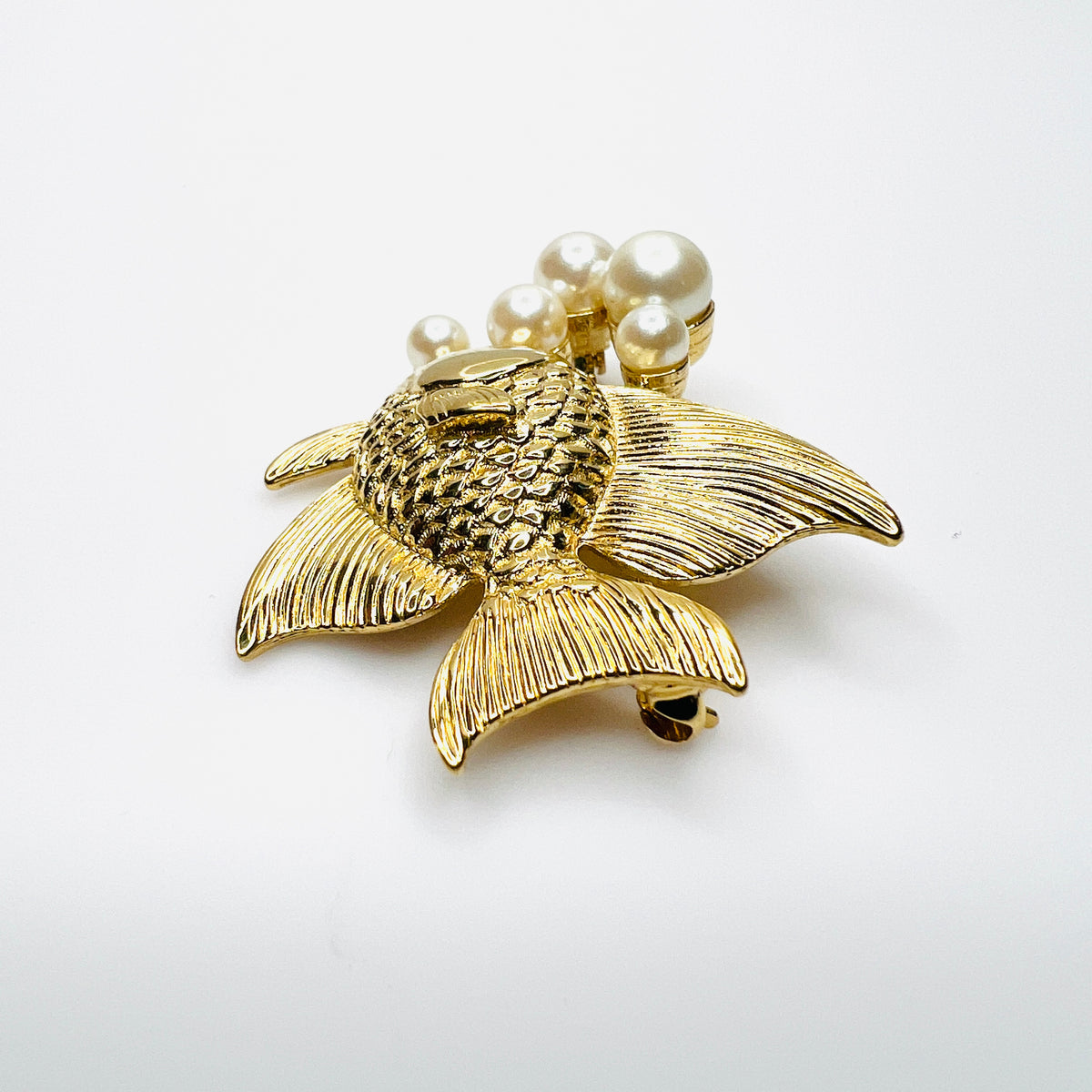 Side view of dimensional gold tone fish brooch with creamy faux pearls