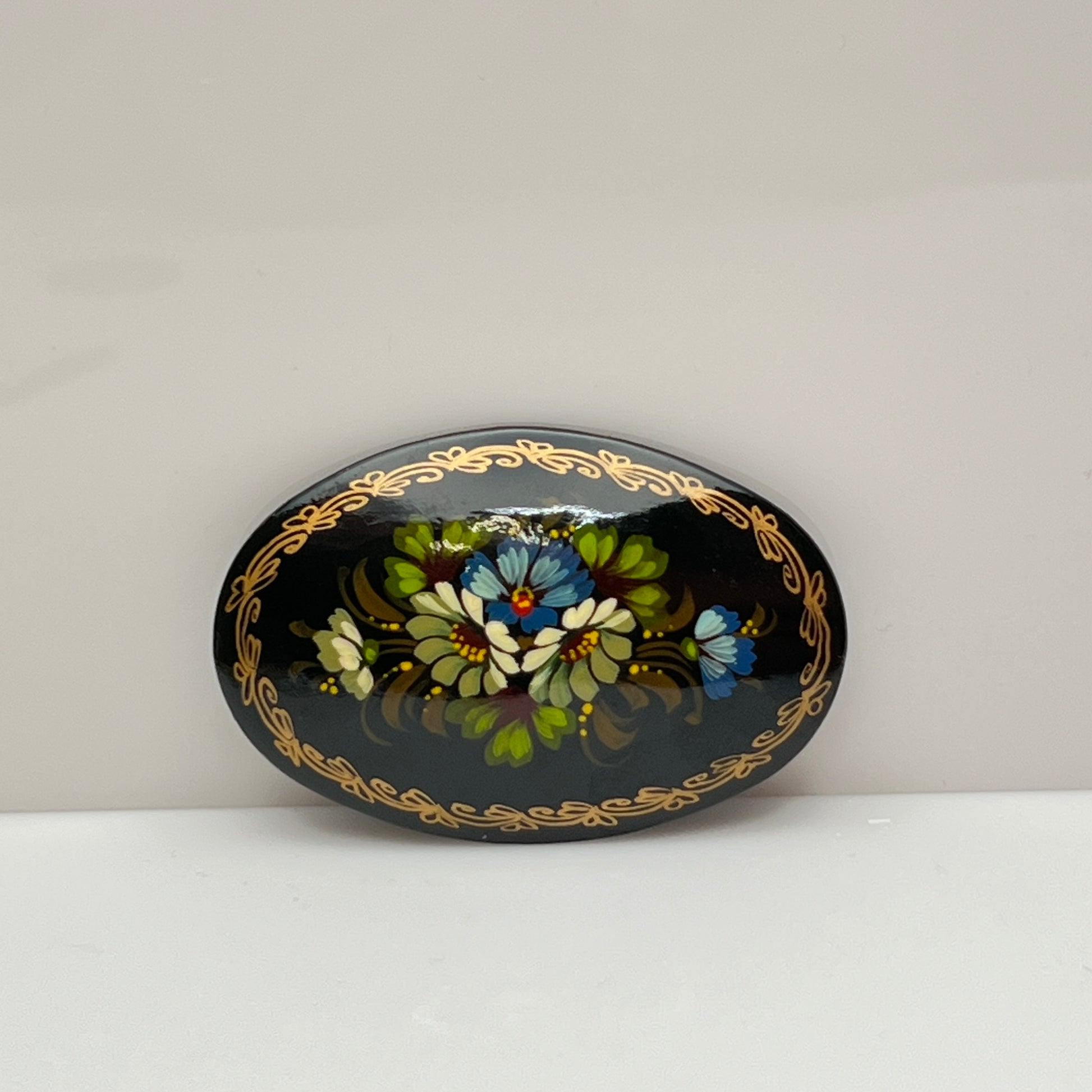 Russian black lacquer brooch with hand-painted floral design and gold border