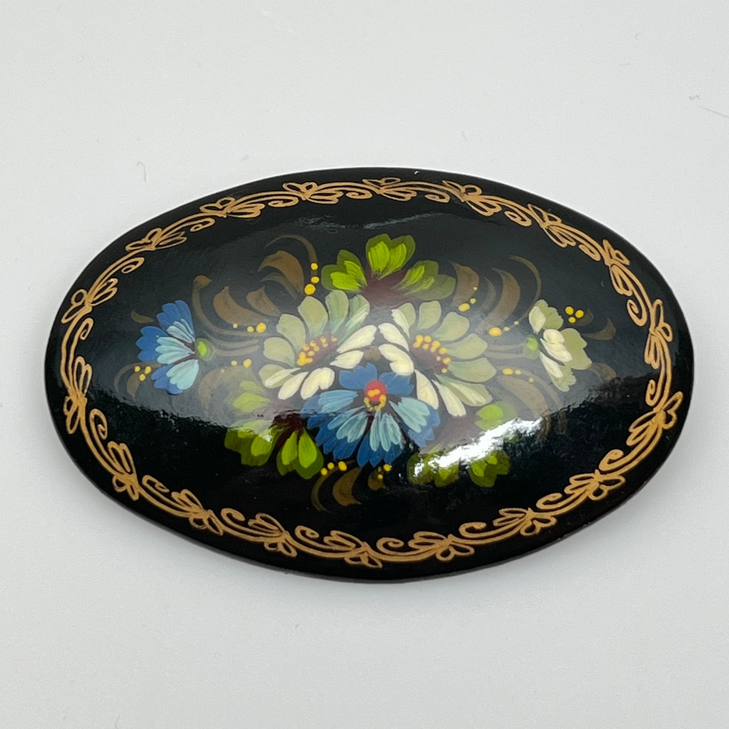 Russian black lacquer brooch with hand-painted floral design and gold border
