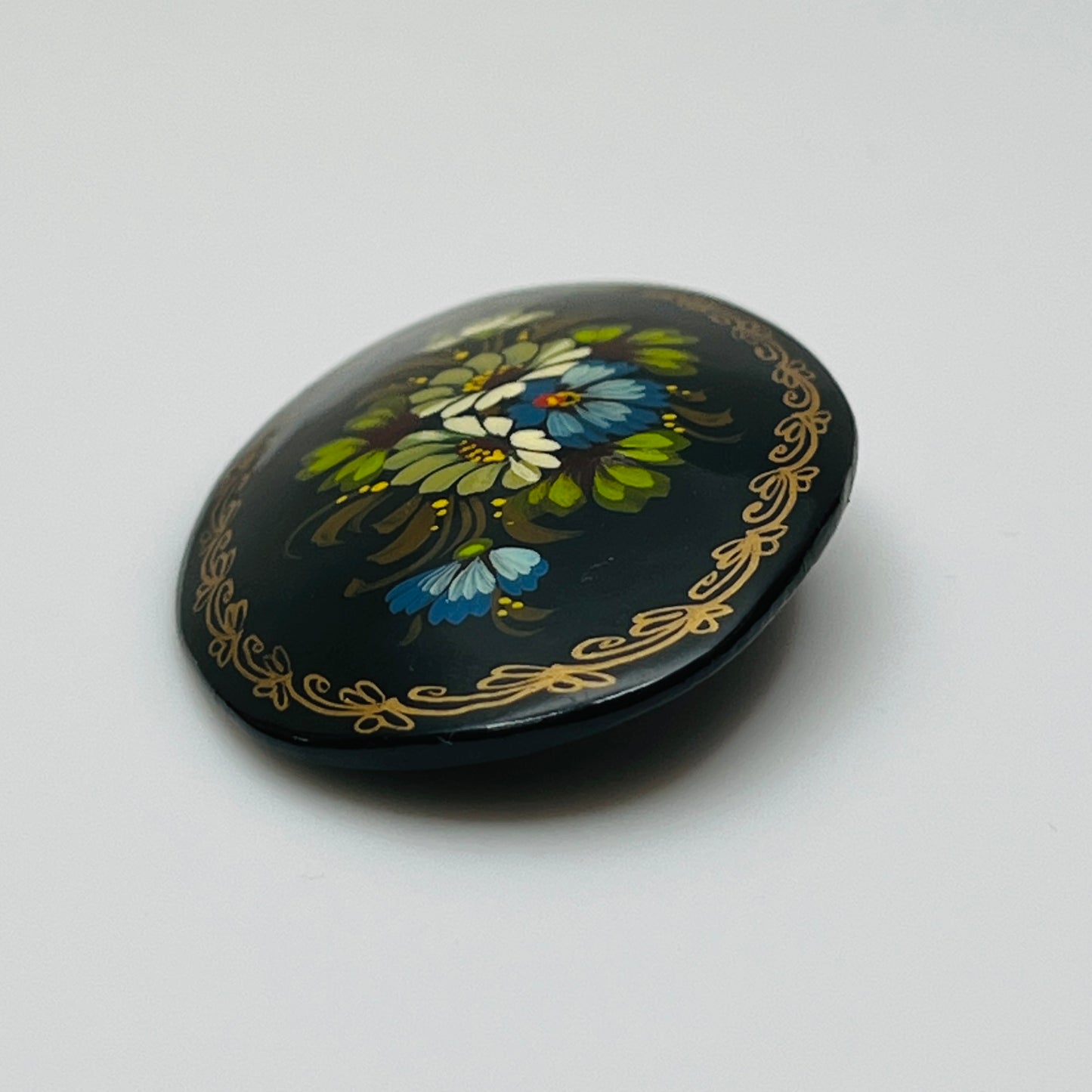 Russian black lacquer brooch with hand-painted floral design and gold border