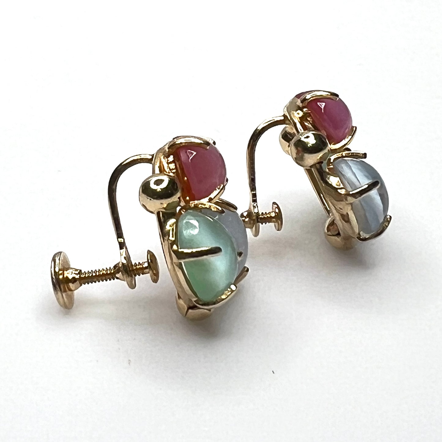 Side view of vintage gold tone screw back earrings with pastel glass cabochons