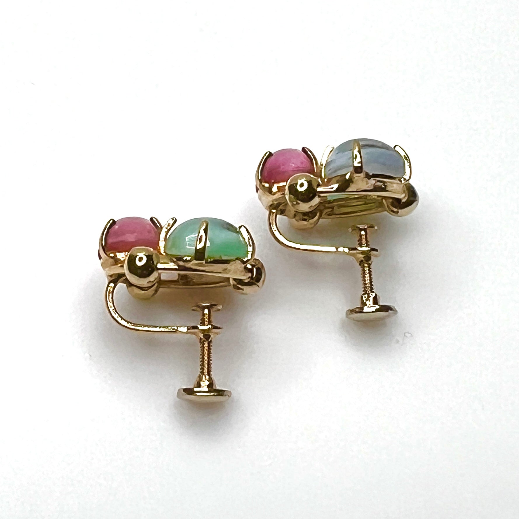 Side view of vintage gold tone screw back earrings with pastel glass cabochons
