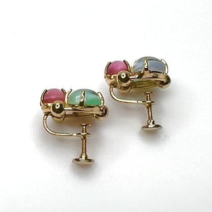 Side view of vintage gold tone screw back earrings with pastel glass cabochons