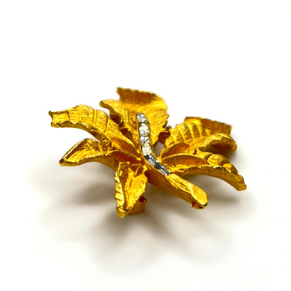 Side profile of vintage textured gold tone leaf brooch with baguette rhinestones