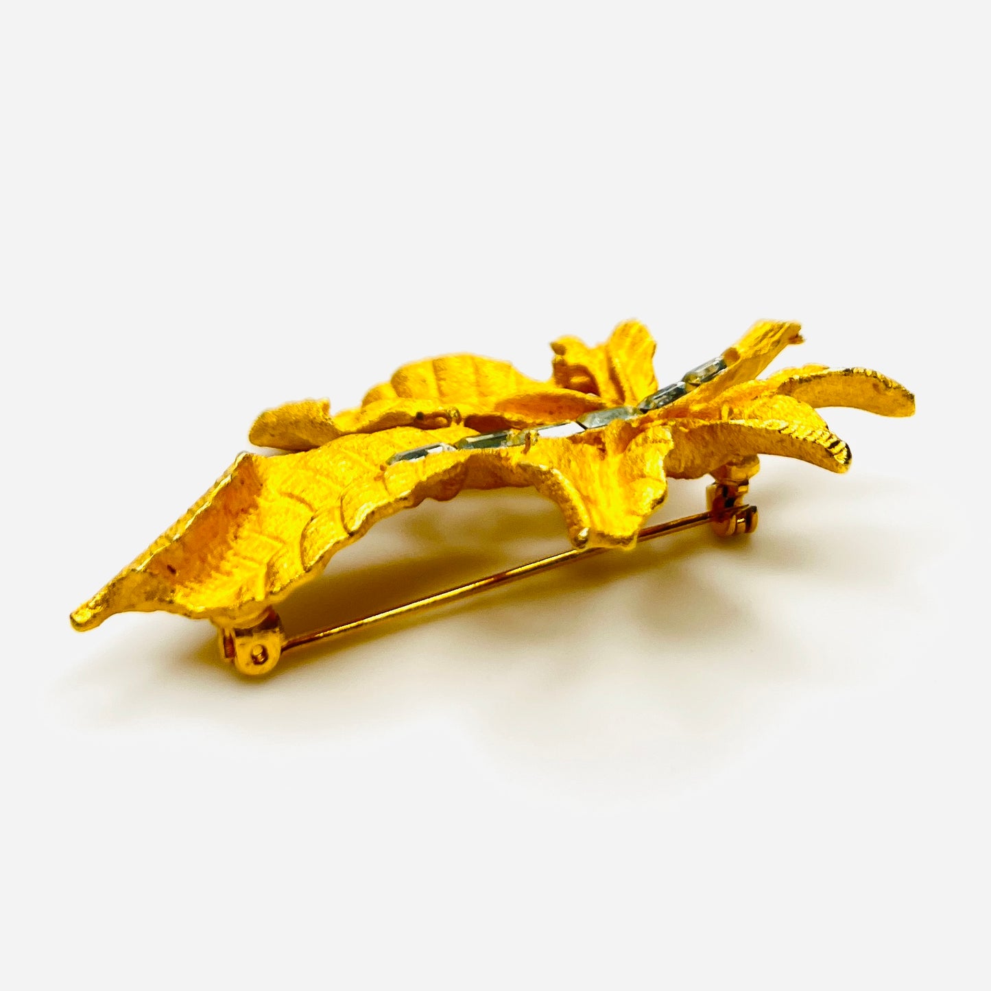 Side profile of vintage textured gold tone leaf brooch with baguette rhinestones