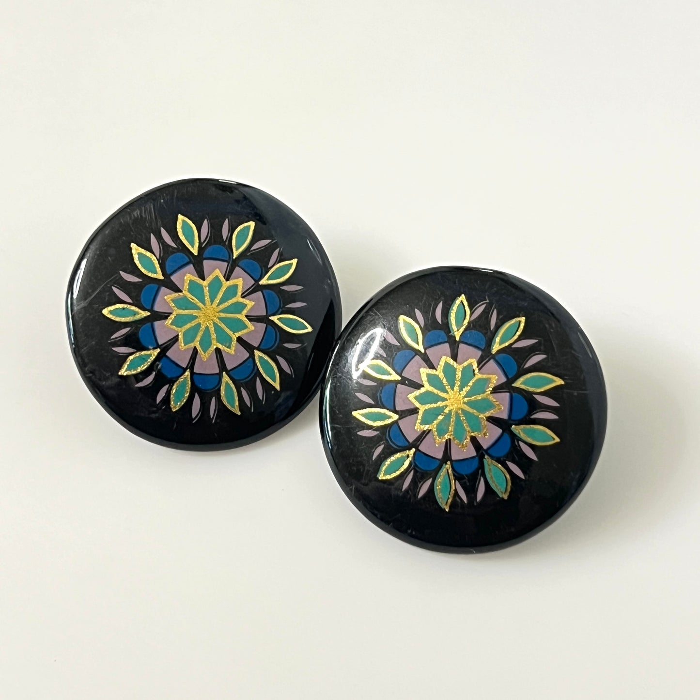 Matching hand-painted floral stud earrings in black, turquoise, blue, and gold enamel