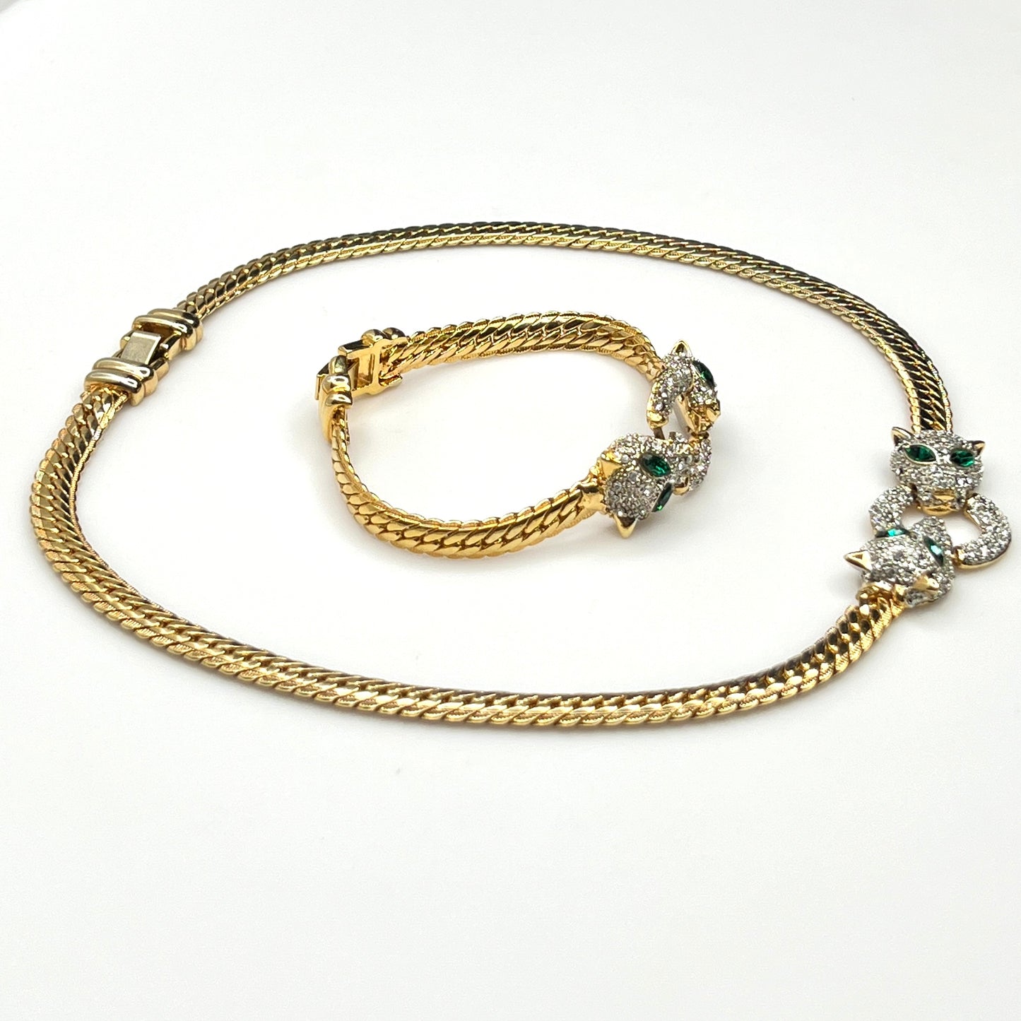 Side view of Vintage necklace and bracelet set with rhinestone panther heads and gold herringbone chains