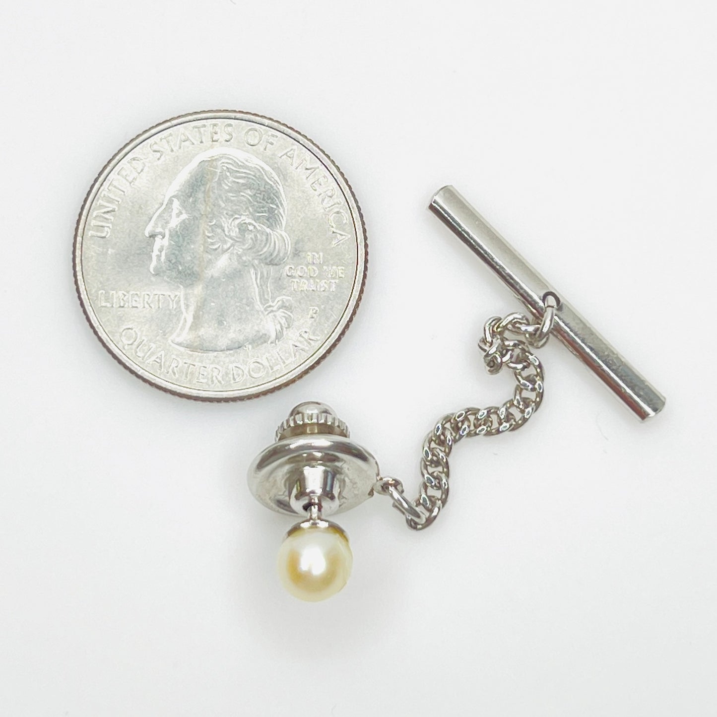 Genuine pearl tie tack with quarter for size reference