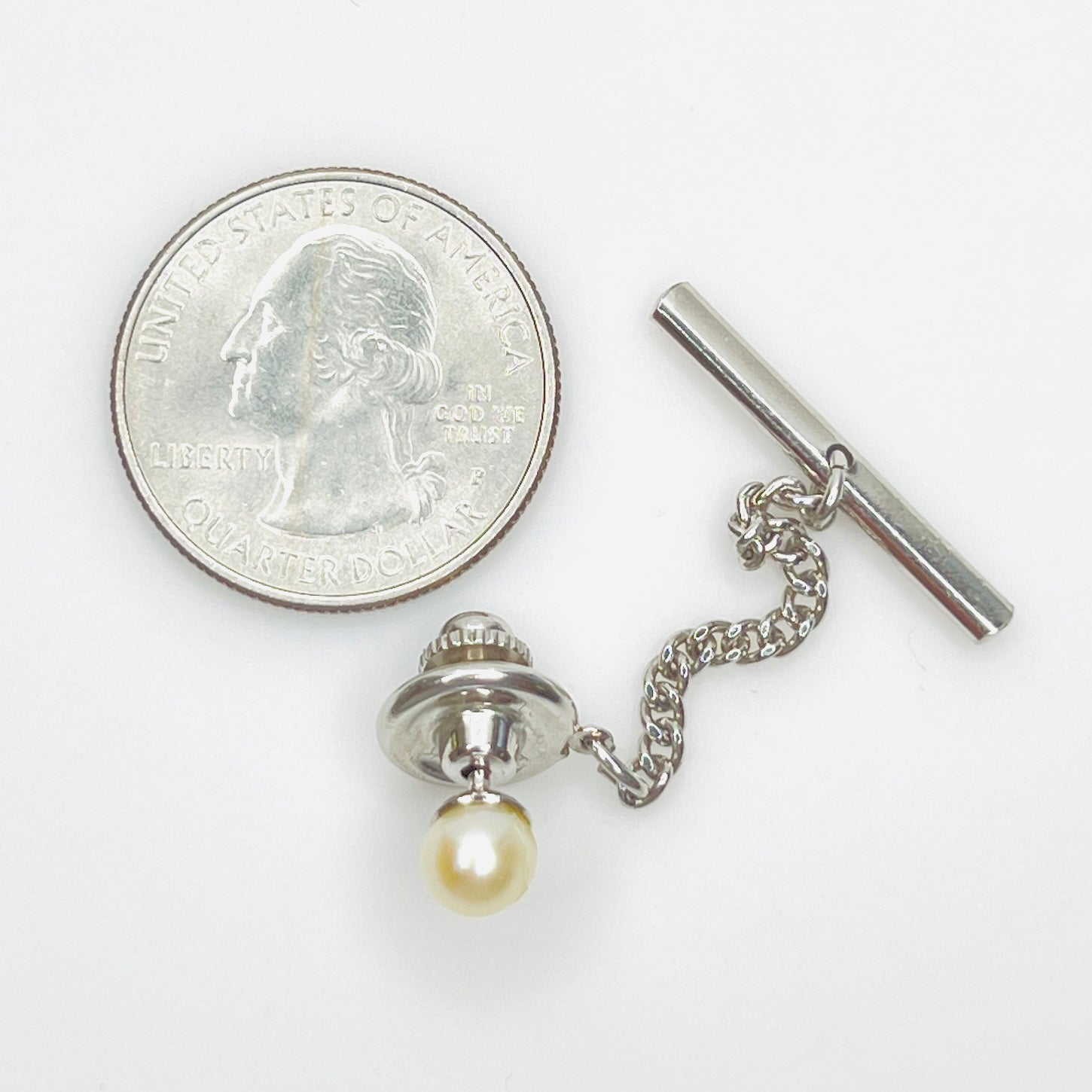Genuine pearl tie tack with quarter for size reference