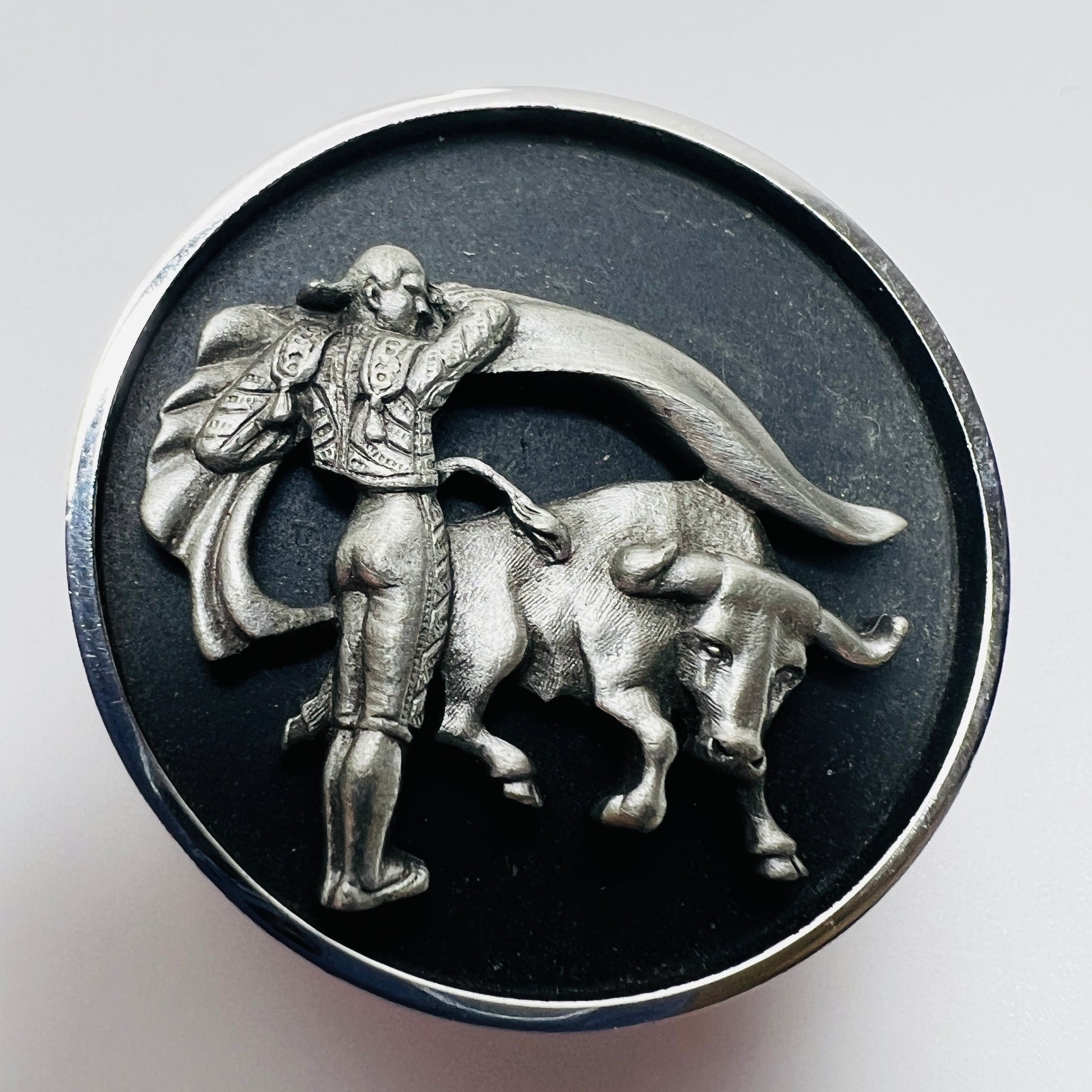 Round tie clip with raised matador and bull silver tone detail