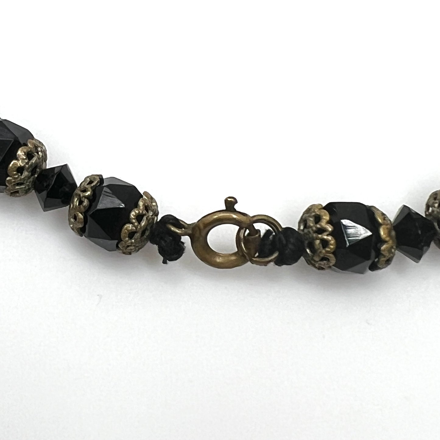 Brass-tone spring ring clasp detail on vintage jet black glass bead necklace